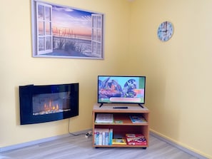 Ein Wohnzimmer mit Flachbildfernseher, Kamin, Bücherregal und Wanduhr.