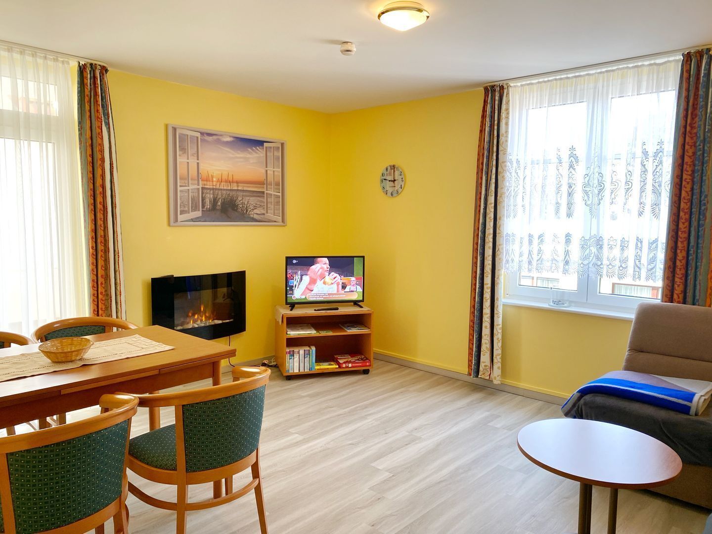 Ein Wohnzimmer mit Fernseher, Kamin, Esstisch, Stühlen und einer Couch.