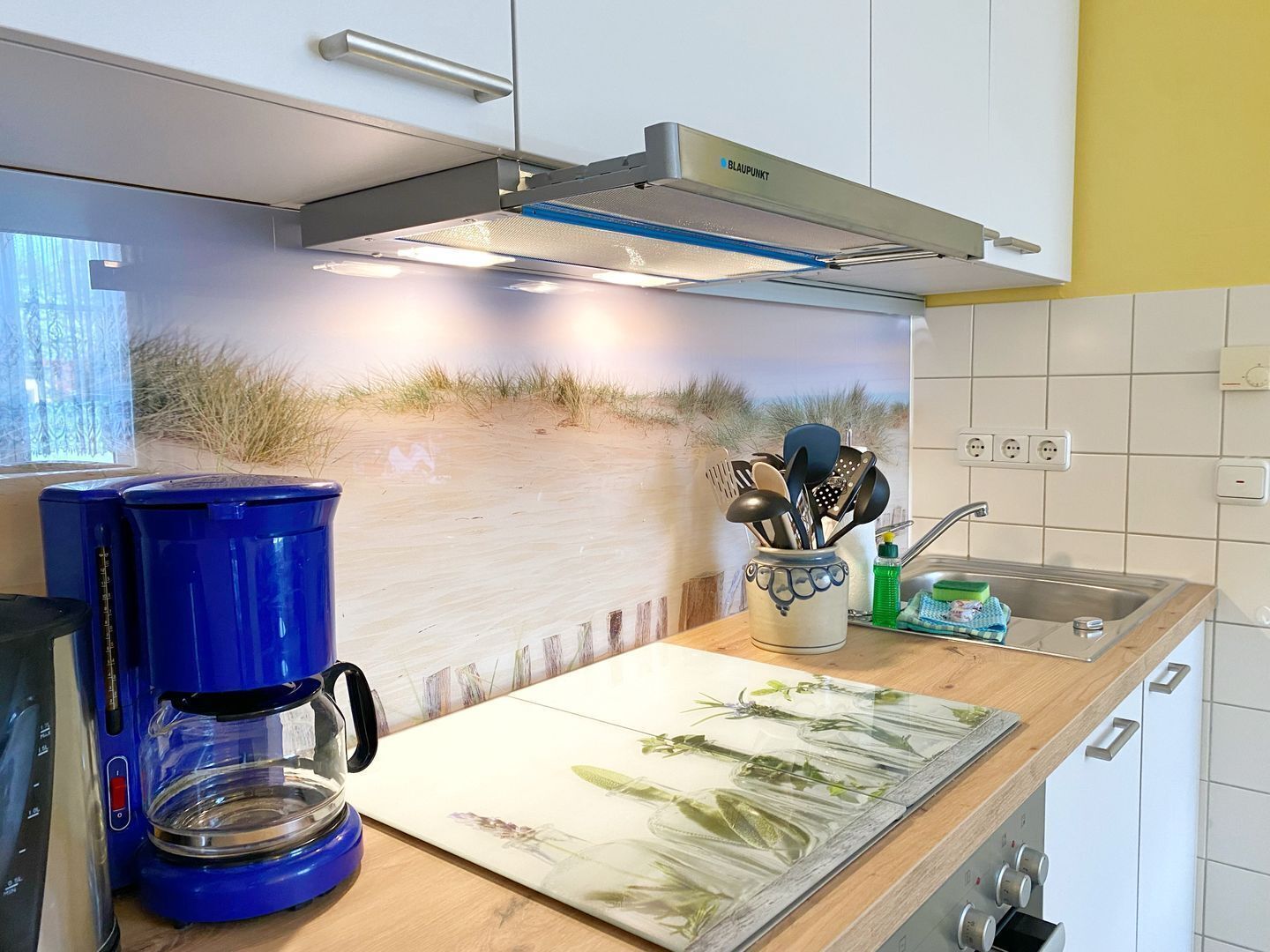 Eine Küche mit Kaffeemaschine, Geschirr und Spüle.