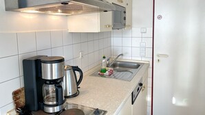 Ett modernt kök med vita skåp, en rostfri köksfläkt, en kaffebryggare och en diskho.