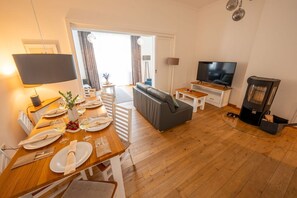 Un salon moderne comprenant un coin repas, un canapé, un téléviseur et un poêle à bois.