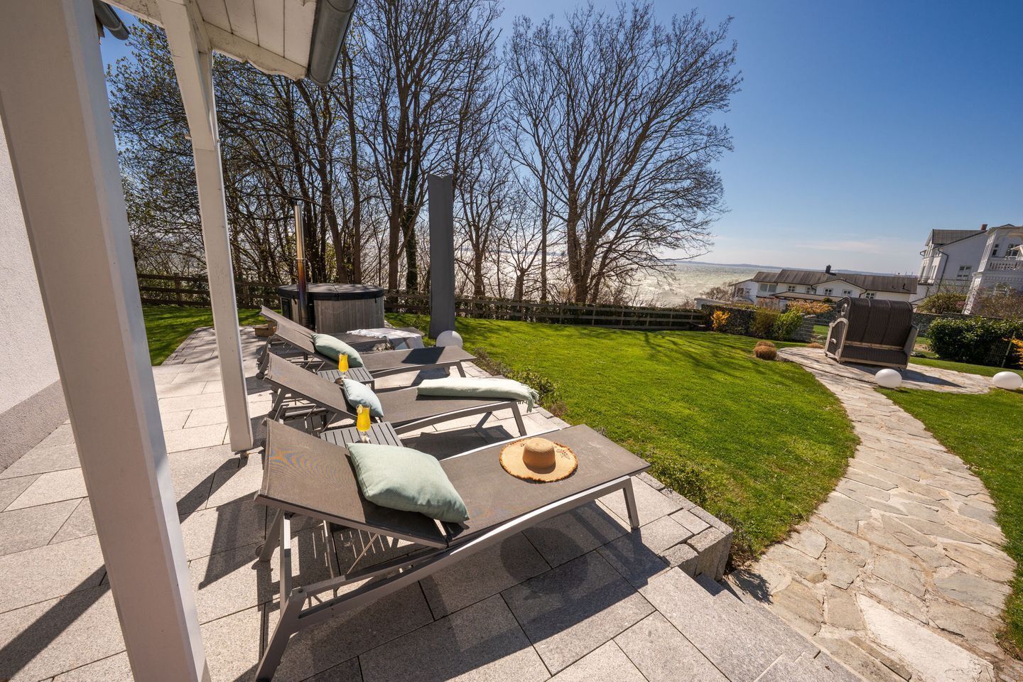 Un patio al aire libre con sillones de descanso y una mesa, un jacuzzi y un sendero de piedra.