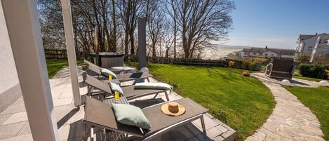 Un patio al aire libre con sillones de descanso y una mesa, un jacuzzi y un sendero de piedra.