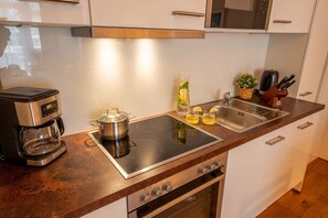 Eine moderne Küche mit Kaffeemaschine, einem Topf auf der Induktionskochplatte, einer Spüle und einem Messerblock.