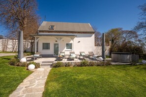 A modern house with a patio, outdoor seating, and a hot tub.