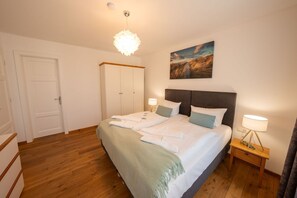 A bedroom with a bed, bedside tables, a wardrobe, and a painting on the wall. - Villa Jenny - Apartment 2 - Villa Jenny Sassnitz (Sassnitz)