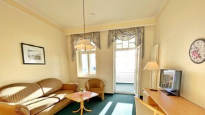 A cozy living room with a sofa, armchair, small table, and a TV. - Sea view apartment no. 21 in the Villa Anna in Sassnitz on Rügen - Sassnitz - (Sassnitz)