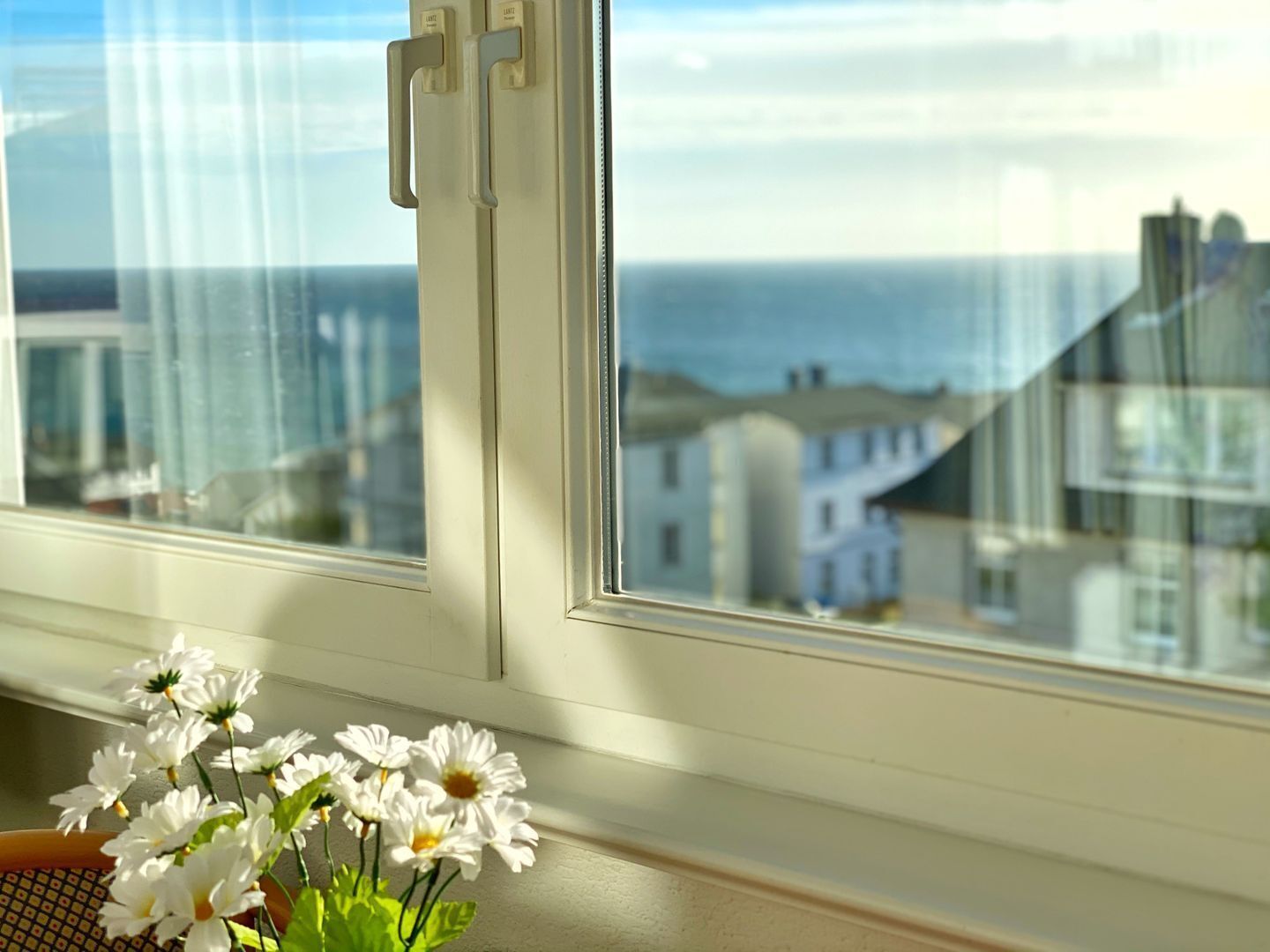 Ein Fenster mit Blick auf Gebäude und das Meer.