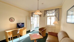 A cozy living room with a sofa, a wooden table, a television, and a chair. - Sea view apartment no. 33 in the Villa Anna in Sassnitz on Rügen - Sassnitz - (Sassnitz)