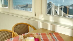 A room with a view of the sea through a window, a wooden table, and two wicker chairs. - Sea view apartment no. 33 in the Villa Anna in Sassnitz on Rügen - Sassnitz - (Sassnitz)