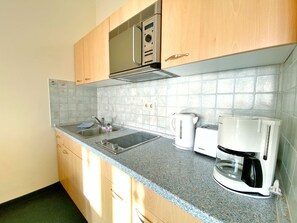 A kitchen with a sink, a kettle, a toaster, and a coffee maker. - Sea view apartment no. 23 in the Villa Anna in Sassnitz on Rügen - Sassnitz - (Sassnitz)