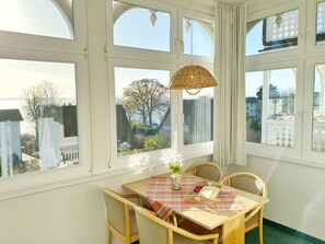 A dining area with a table set for two, surrounded by large windows offering a view of the cityscape.