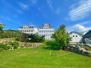 A large, white, multi-story building with a symmetrical facade and arched windows, surrounded by a well-maintained lawn and stone walls. - Sea view apartment no. 23 in the Villa Anna in Sassnitz on Rügen - Sassnitz - (Sassnitz)