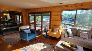 Ein gemütliches Blockhausschlafzimmer mit Essbereich, einer Couch und Blick auf einen See.