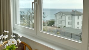 Una habitación con vista al mar y un edificio blanco al otro lado de la calle.