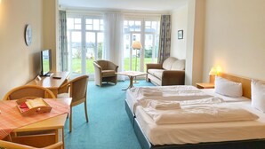 A hotel room with a bed, two armchairs, a desk with a computer, and a view of the outdoors. - Vacation apartment 10 in the Villa Anna in Sassnitz - Sassnitz - Villa Anna (Sassnitz)
