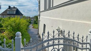 A gated entrance with a wrought iron gate, a pathway leading to a house, and a clear sky. - Vacation apartment 10 in the Villa Anna in Sassnitz - Sassnitz - Villa Anna (Sassnitz)