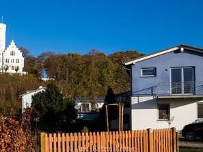 A residential area with a white building with a tower, a modern house, and a wooden fence.