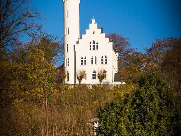 Un edificio grande y blanco, similar a un castillo, con una torre destacada, rodeado de árboles.