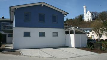 Una casa de dos pisos con fachada azul y blanca, un garaje y un cobertizo pequeño.