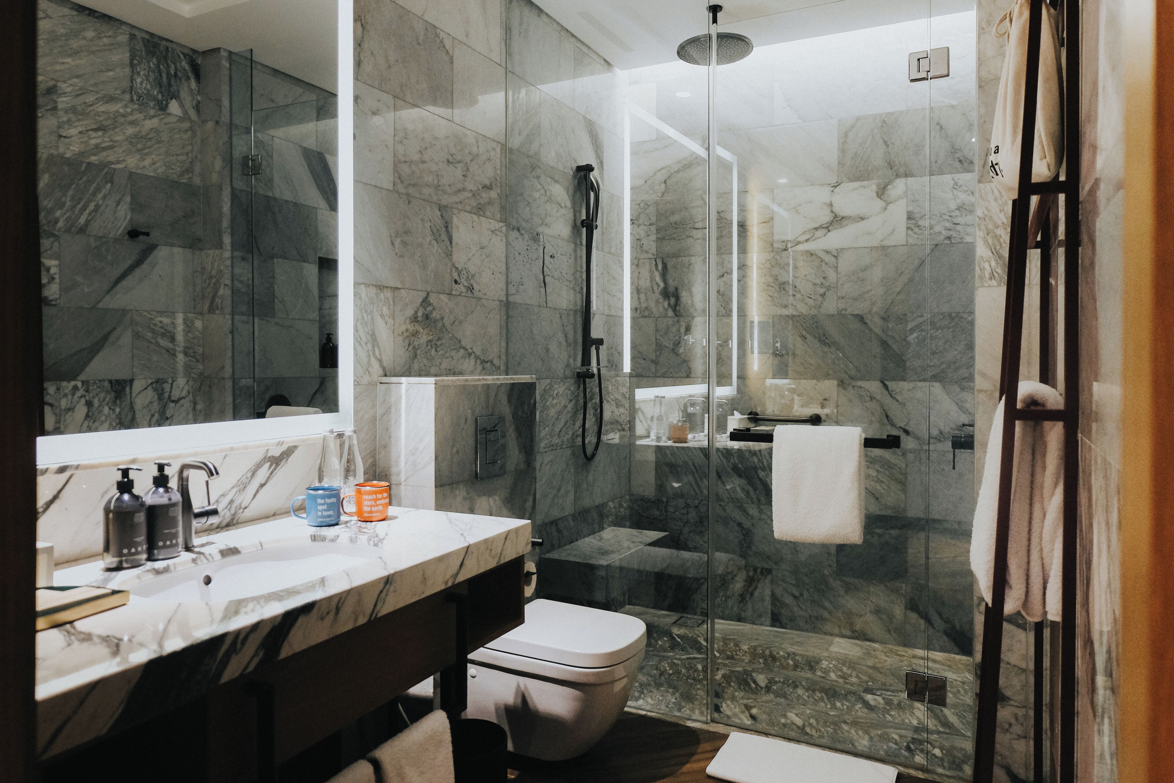 A modern bathroom with a marble sink, a toilet, and a glass-enclosed shower area.