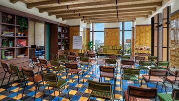 Una biblioteca con suelo de cuadros, estanterías de madera y vistas de la ciudad a través de amplios ventanales.