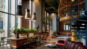 A modern interior with a wooden bar, leather seating, and a spiral staircase. - 25hours Hotel Jakarta The Oddbird (Jakarta)