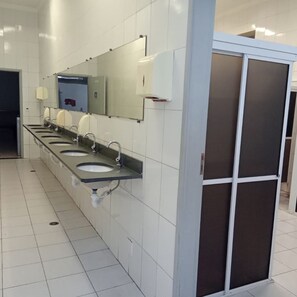 A public restroom with multiple sinks, a large mirror, and a privacy partition.