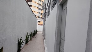 A narrow corridor with tiled flooring, white walls, and a door on the right. - Pousada Baraúna (Santos)