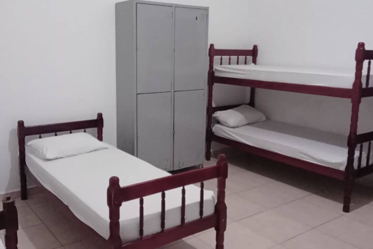 Ein Zimmer mit einem Einzelbett, einem Etagenbett und einem grauen Kleiderschrank.