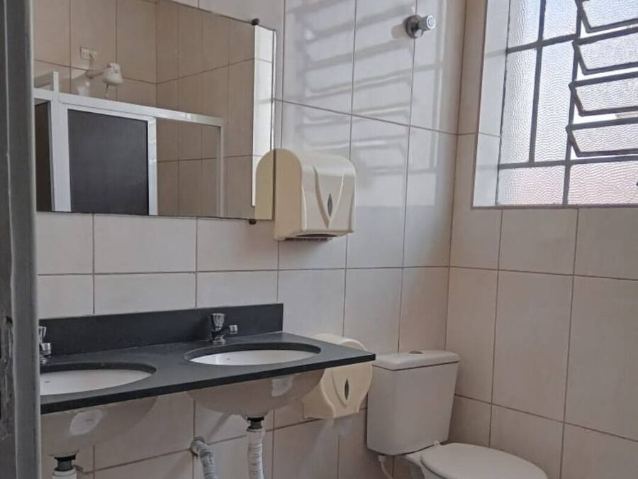 A bathroom with two sinks, a toilet, a mirror, and a window with a grid pattern.