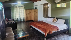 A bedroom with a bed, a wooden wardrobe, a glass table, and a ceiling fan. - Remarkable 1-Bed House in Bhimtal (Bhimtal)