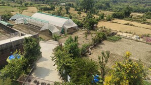 A rural landscape with a greenhouse, fields, and distant hills. - Remarkable 1-Bed House in Bhimtal (Bhimtal)