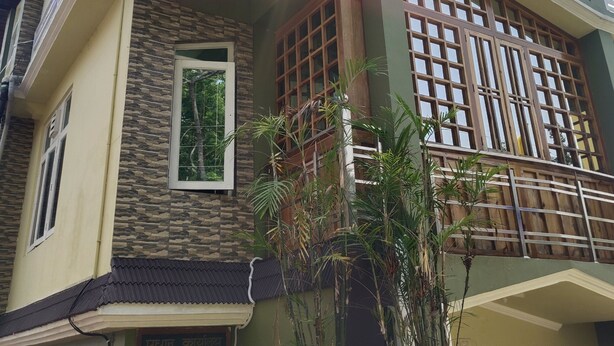 A two-story house with a balcony, a window, and a potted plant. - Remarkable 1-Bed House in Bhimtal (Bhimtal)