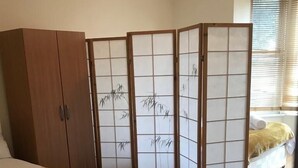 A bedroom with a bed, a wardrobe, a shoji screen, and a small potted plant.