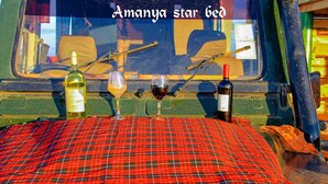A vehicle interior with a red and black checkered tablecloth, three wine bottles, and two wine glasses.