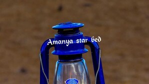 A blue lantern labeled "Amanya star bed" on a wooden bench.