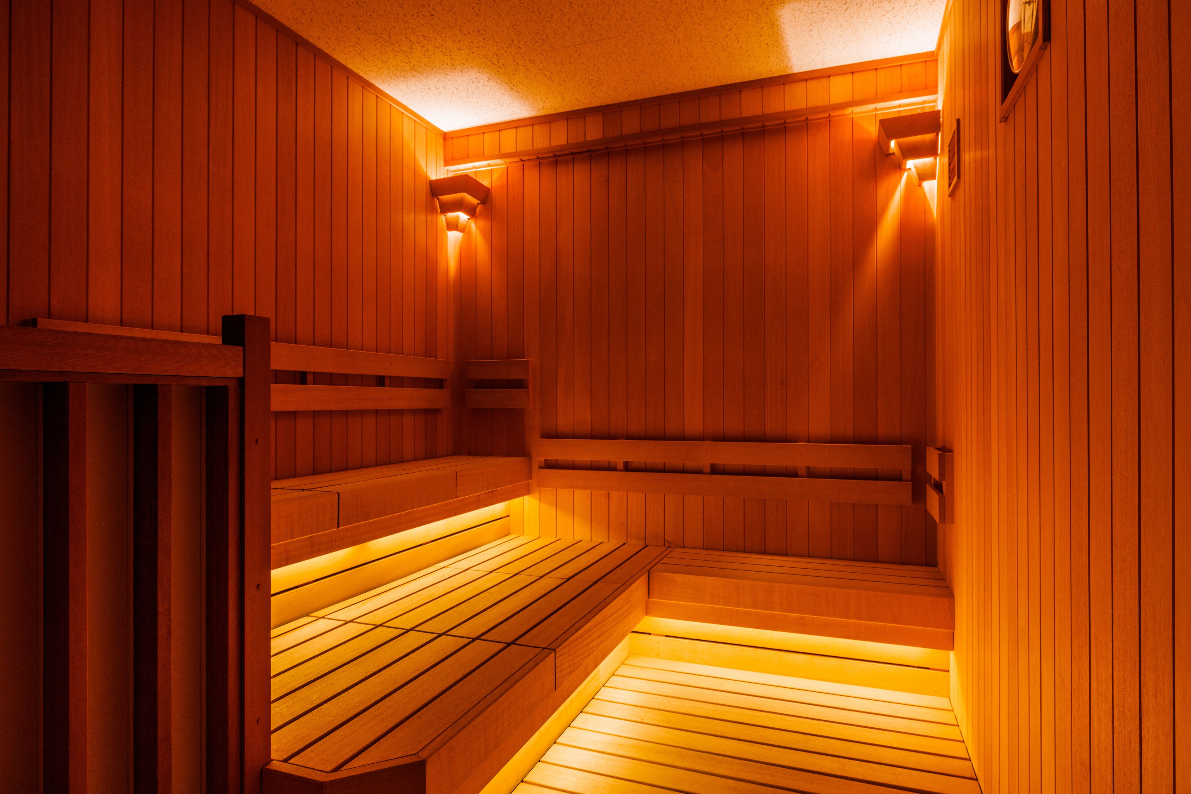 A sauna with wooden benches and walls, and a ceiling light fixture.