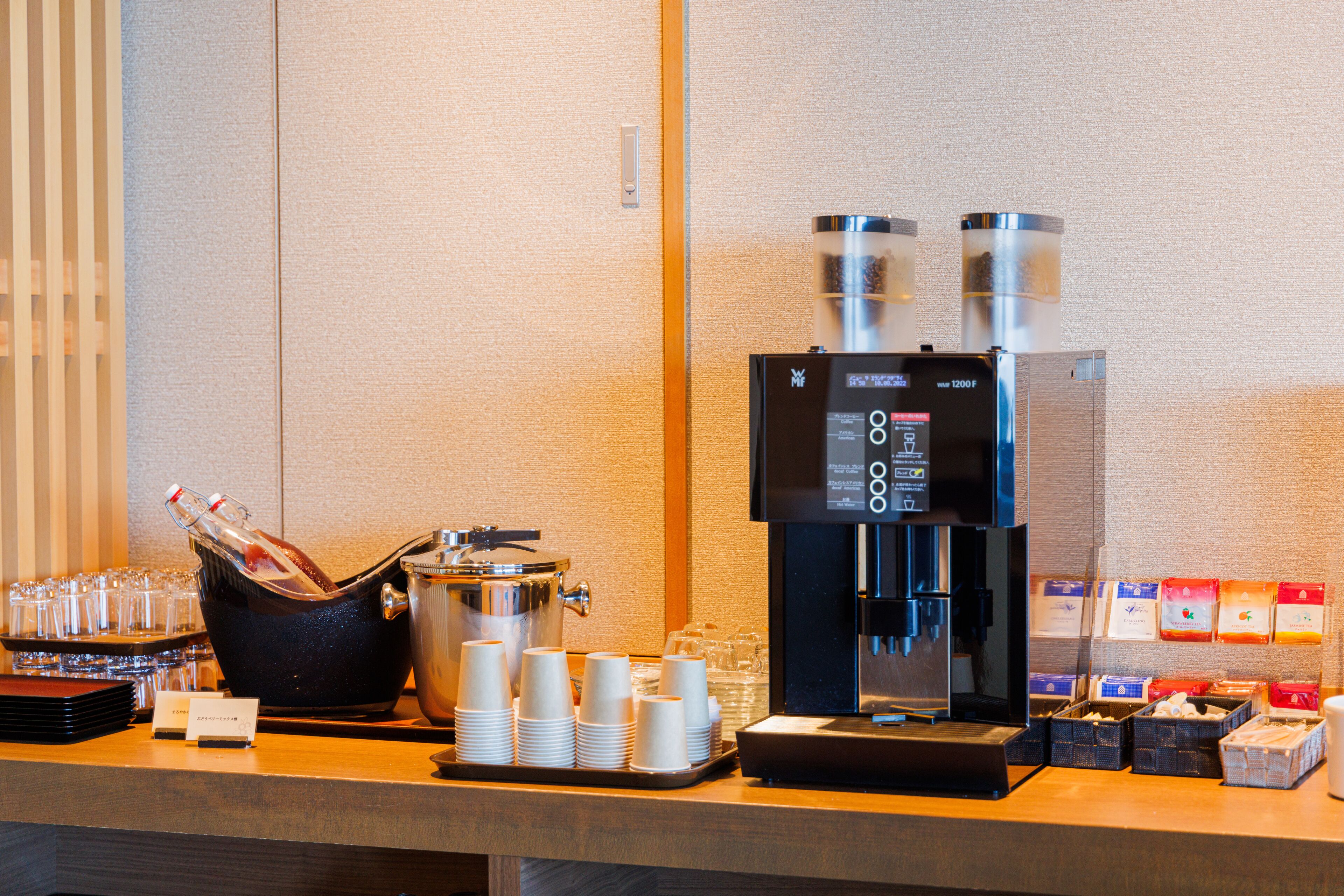 A coffee station with a coffee machine, cups, and a beverage dispenser.