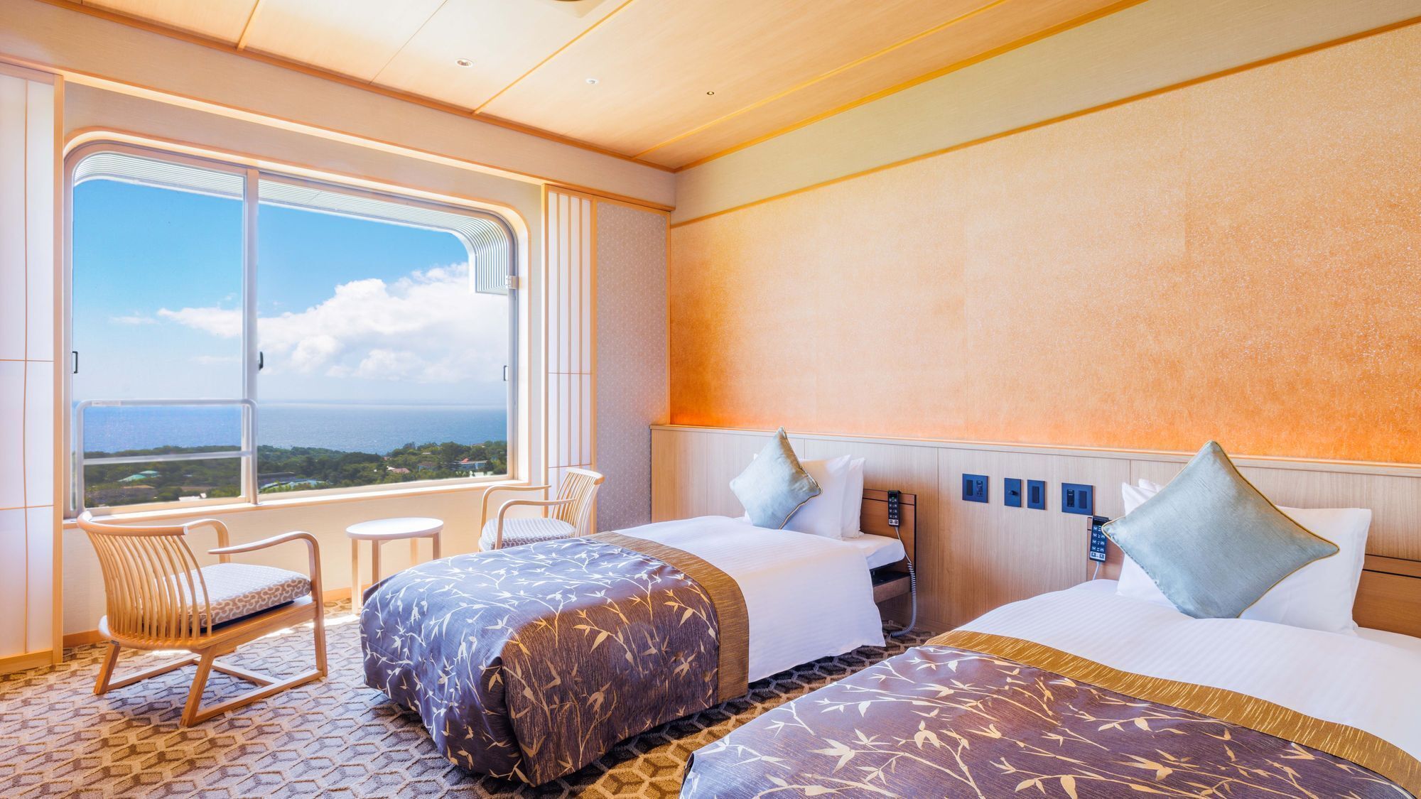 A hotel room with two beds, a balcony with a view, a small table, and a chair.
