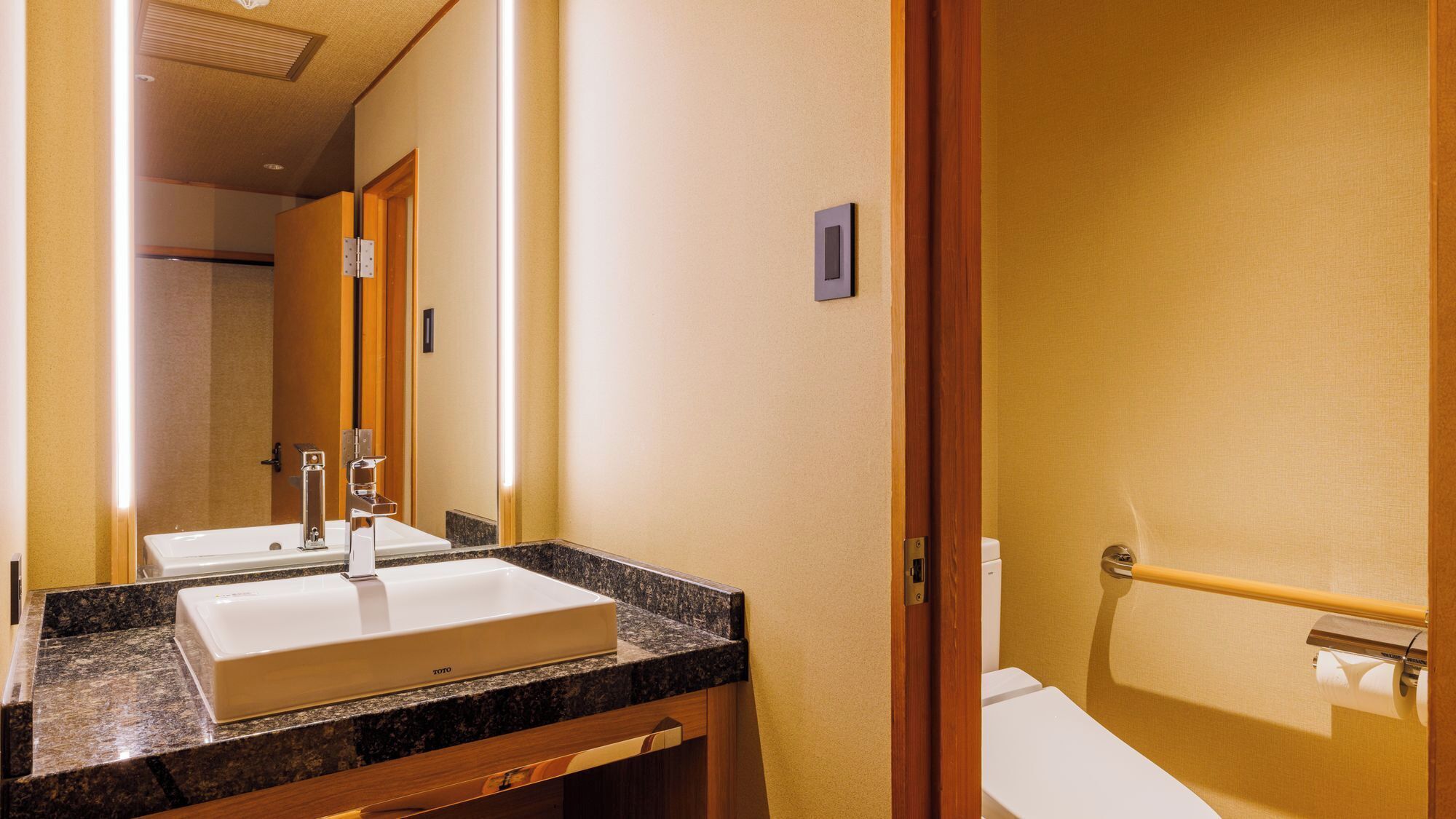 Un baño de hotel con lavamanos doble, espejo e inodoro.