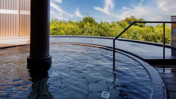 A hot tub area with a stone wall and a wooden deck.