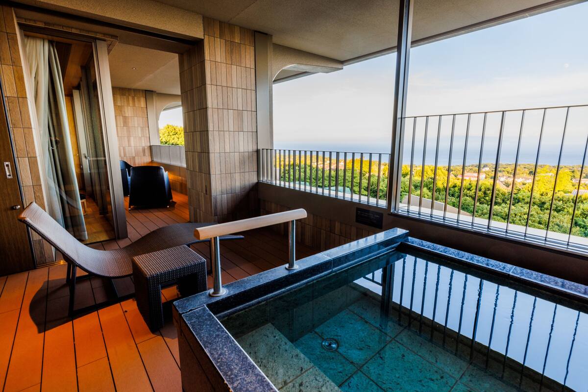 Un balcon avec une piscine, un fauteuil de relaxation et une vue sur le paysage.