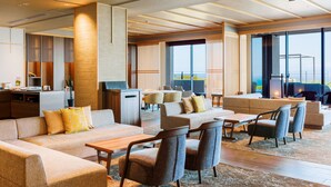 Un moderno vestíbulo de hotel con una zona de estar, un mostrador de recepción y grandes ventanales que ofrecen vistas.
