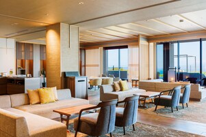 A modern hotel lobby with a seating area, a reception desk, and large windows offering a view.