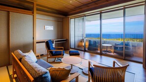 Un interior moderno con un sofá, sillas y una mesa. Amplias ventanas ofrecen vistas al océano.