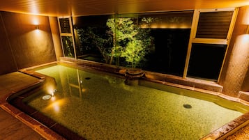 A hot spring bath with a view of trees outside.