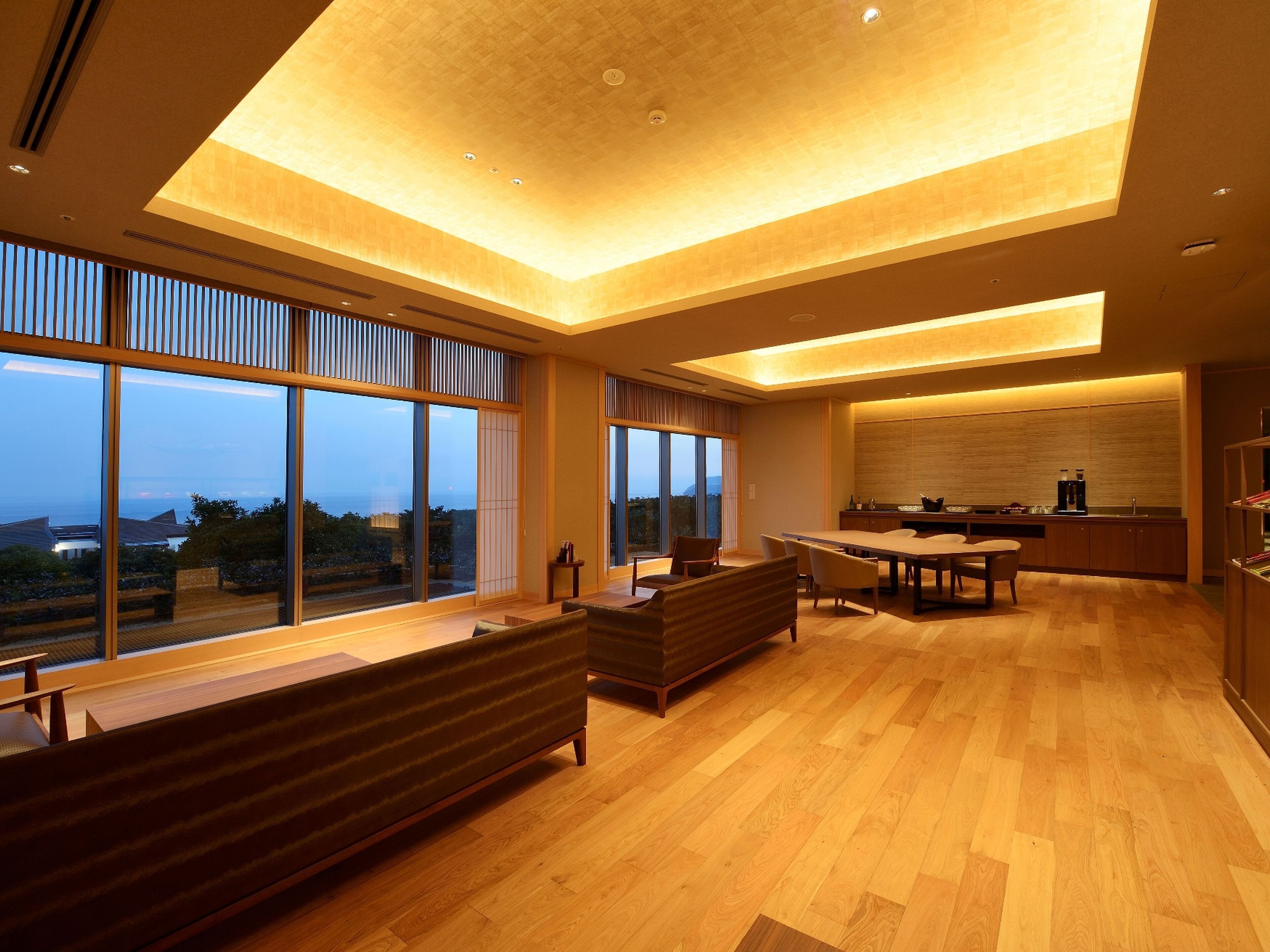 Un interior moderno con comedor, cocina y ventanas amplias que ofrecen vista al mar.