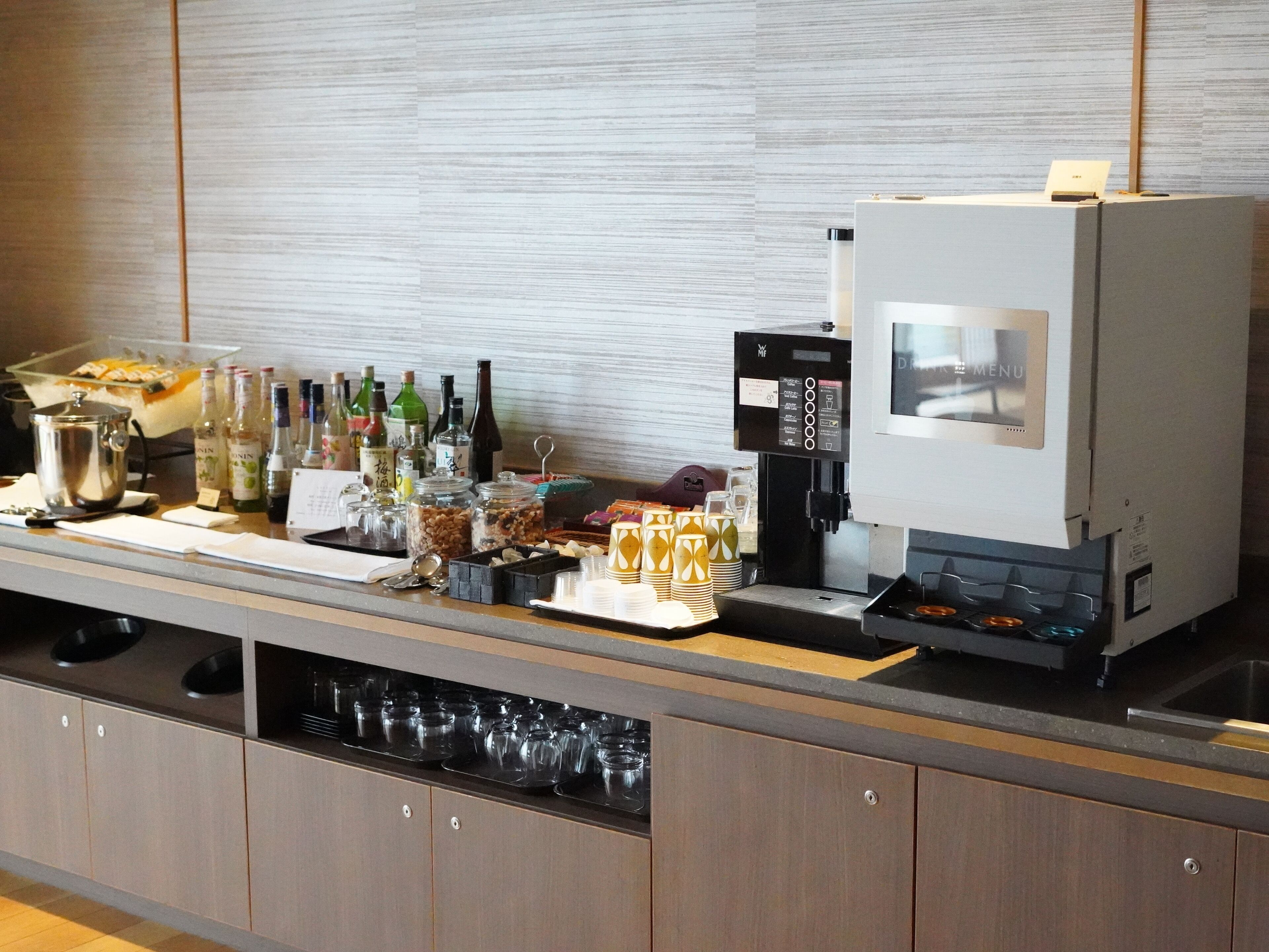 A bar area with a coffee machine, various bottles, and glasses.