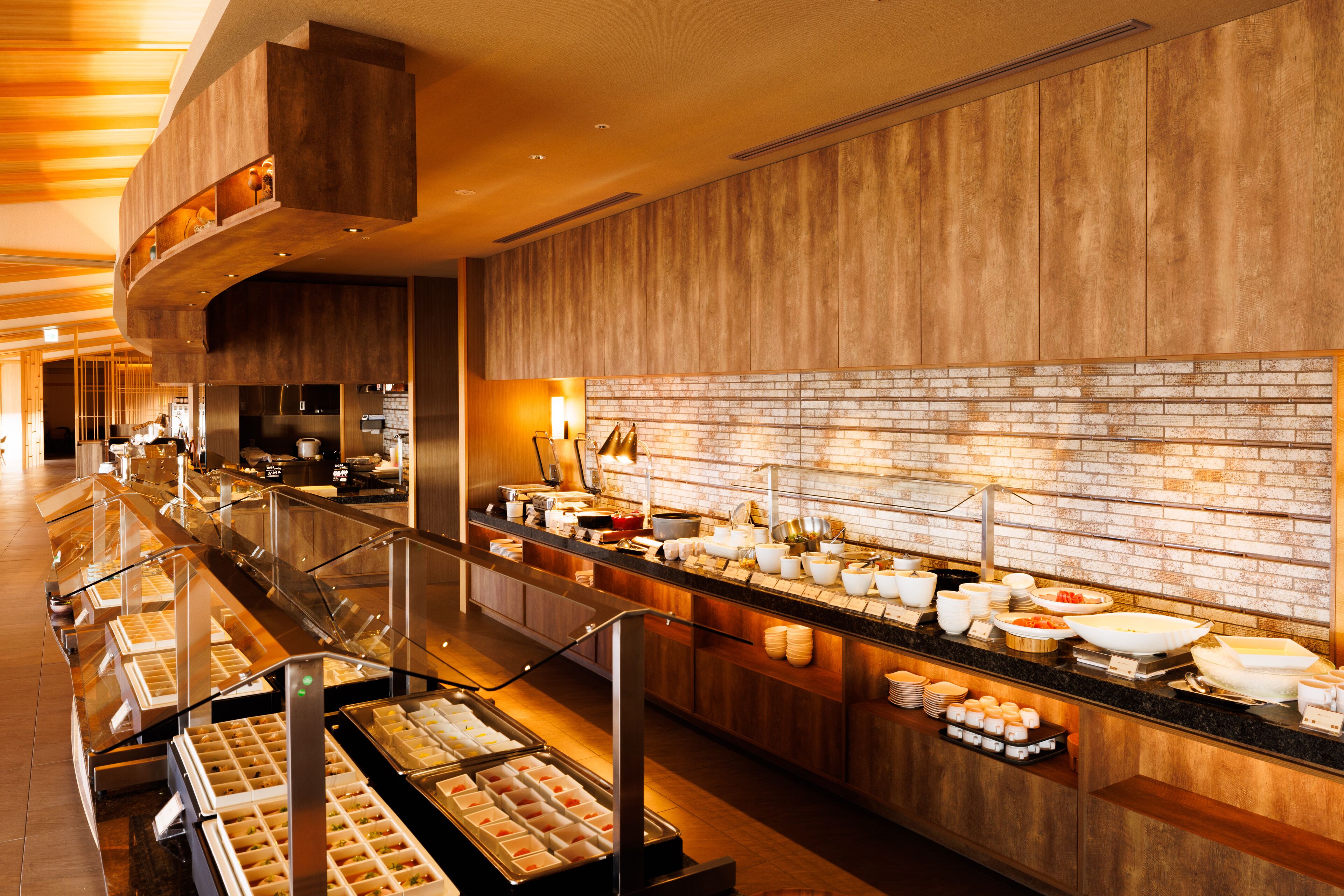 A buffet area with multiple food stations, a brick wall, and a wooden ceiling.